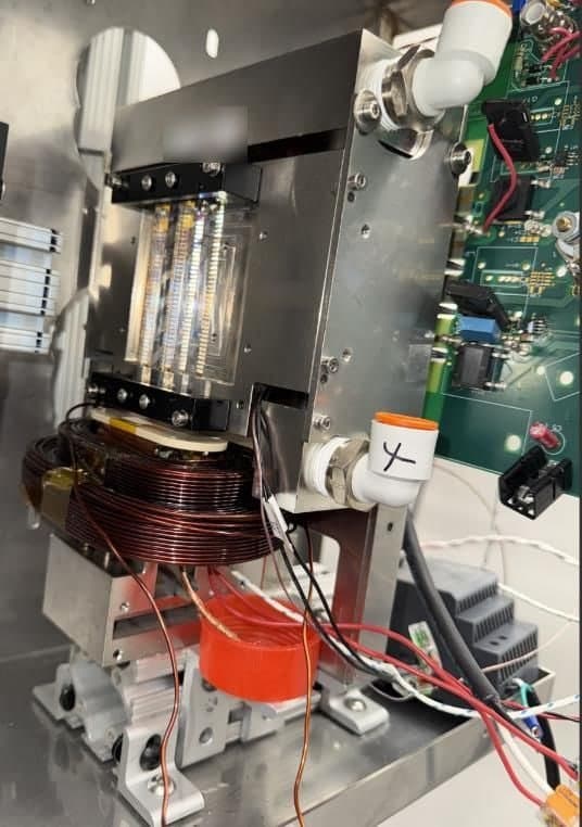 A line-locked diode pump module on a laboratory bench: a diode laser stack in a metal housing with coolant fittings, mounted above a copper magnet coil.